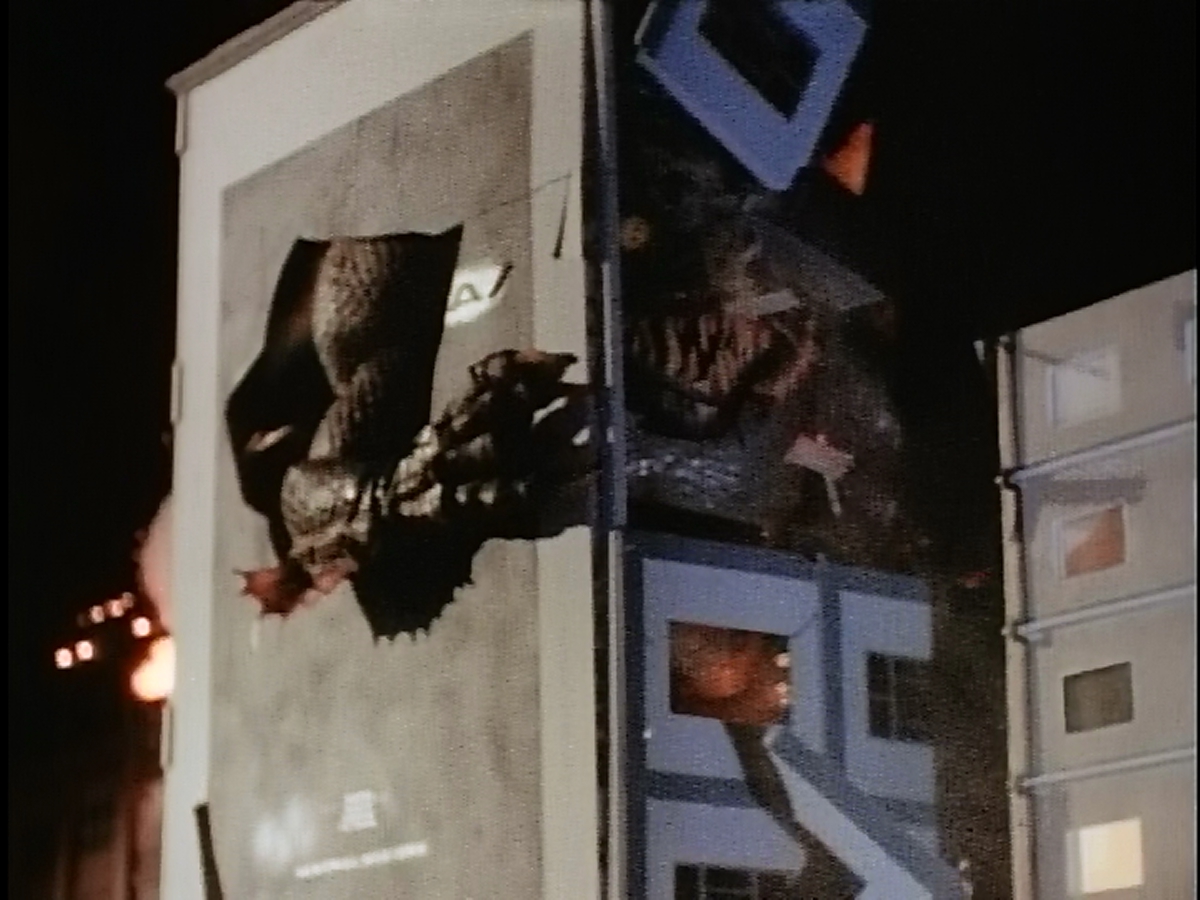 Kraa punches through a 1998-ubiquitous Godzilla advertisement.