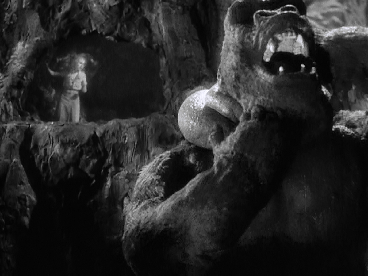 Kong is torn between grabbing Jack Driscoll and saving Ann Darrow.