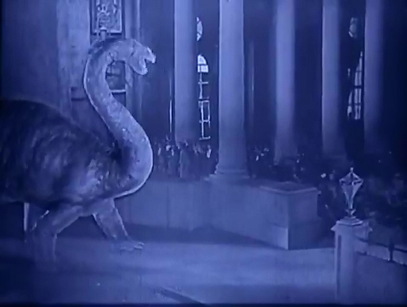 In the foreground, a dinosaur. In the background, actors. From the 1925's The Lost World.